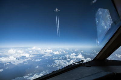 Airplane flying in sky seen through glass window