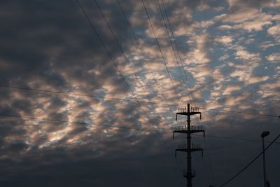 Low angle view of silhouette electricity pylon against sky at sunset