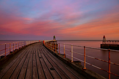 Pier over sea against sky during sunset