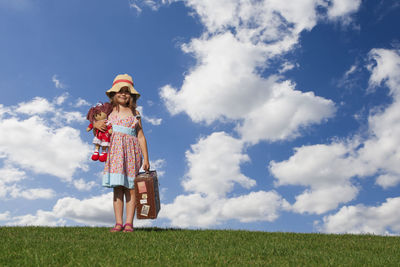 Girl standing on field against sky