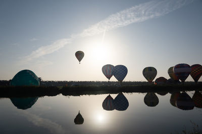 Hot air balloons in lake against sky during sunset