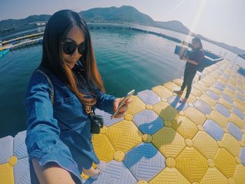 Woman wearing sunglasses sitting by sea