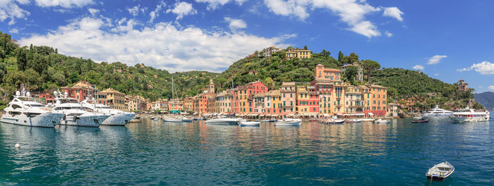 Sailboats moored on river by buildings in city against sky