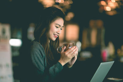 Smiling woman with coffee cup sitting in cafe