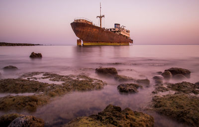 Abandoned ship on sea during sunset