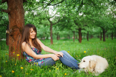 Woman with dog sitting on field