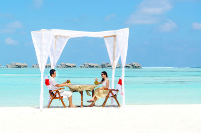 Couple dating at beach against sky