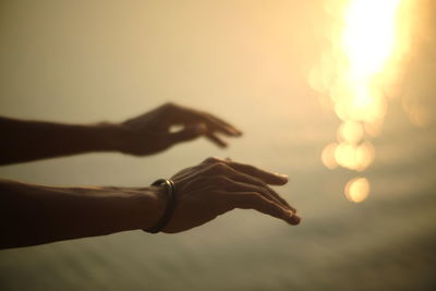 Close-up of hands against sky during sunset