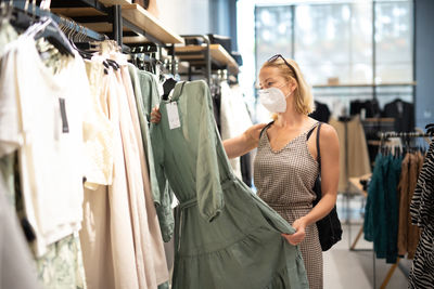 Mid adult woman wearing flu mask shopping at clothing store