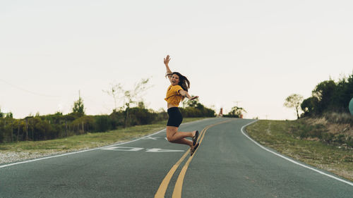 Man jumping on road against clear sky