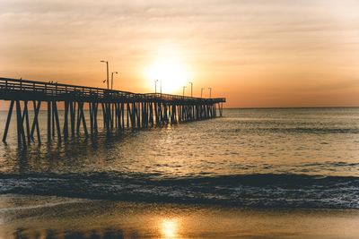 Pier over sea against sky during sunset