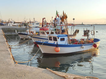 Fishing boats in sea at sunset