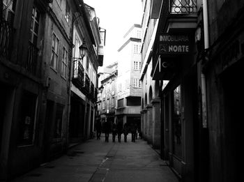 People walking on footpath amidst buildings in city