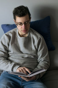 Portrait of young woman using laptop while sitting on sofa at home