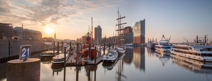 Sailboats moored in hamburg harbor against elbphilharmonie on sunrise