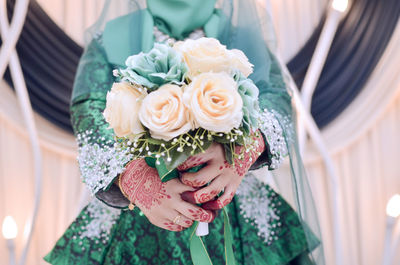 Midsection of bride holding rose bouquet during wedding