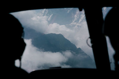 Silhouette pilots flying plane over mountain