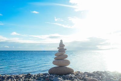 Stack of pebbles on beach against sky