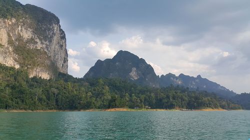 Scenic view of sea by mountains against sky