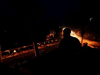 Rear view of silhouette man against illuminated light at night