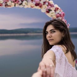 Portrait of beautiful woman standing by sea against sky