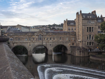 Arch bridge over river against buildings in city