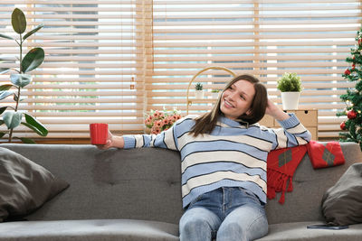 Portrait of smiling woman sitting on sofa at home