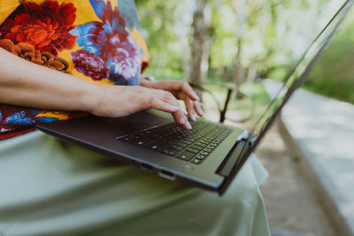 Office outdoors, close-up of female hands typing on keyboard with laptop
