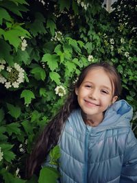 Portrait of young woman standing against plants