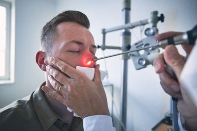 Cropped hand of doctor examining patients nose