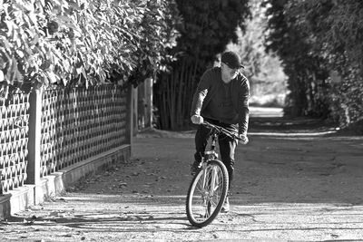 Rear view of man riding bicycle on road