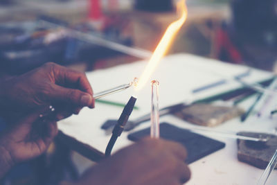 Cropped hands of worker shaping glass on welding torch