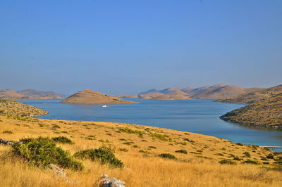 Scenic view of sea and mountains against clear blue sky