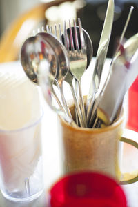 Close-up of fork and spoons in mug on table