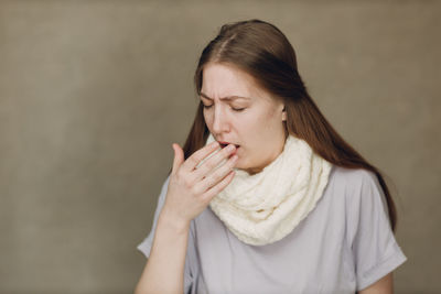 Young woman looking away against wall