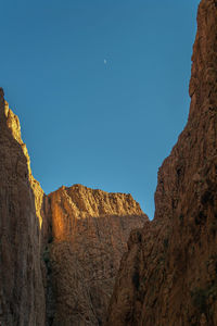 Low angle view of rocky mountains against clear blue sky