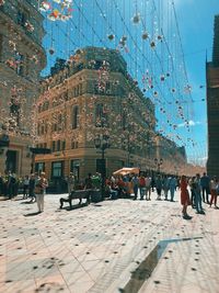 People walking on street against buildings in city