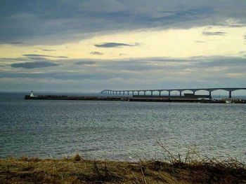 Bridge over river against cloudy sky