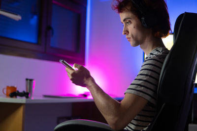 Man using mobile phone while sitting in darkroom