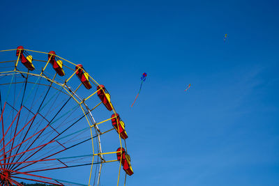 Low angle view of ferris wheel against clear blue sky