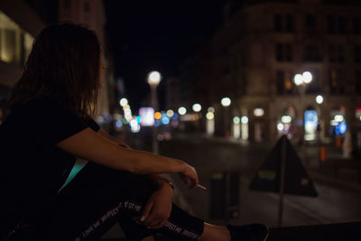 Side view of woman on illuminated street at night