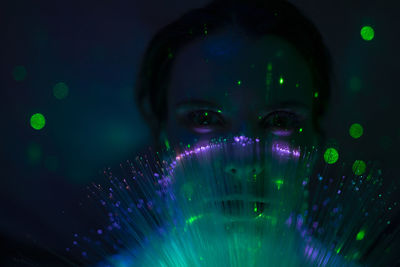 Portrait of beautiful young woman against illuminated background