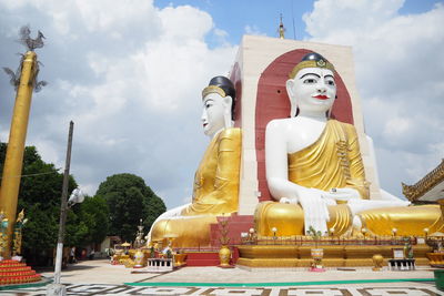 Statue against temple and building against sky