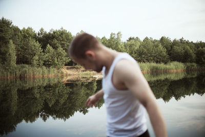 Side view of man standing by lake against sky