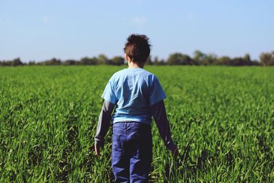 Rear view of boy on field against sky