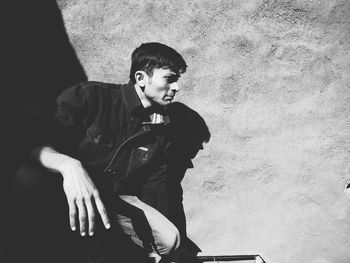 Portrait of boy sitting against wall