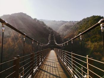 Footbridge over mountain against sky