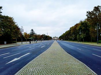 Road by trees against sky