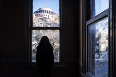 Rear view of woman standing in window