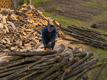 Full length of man working on log in forest